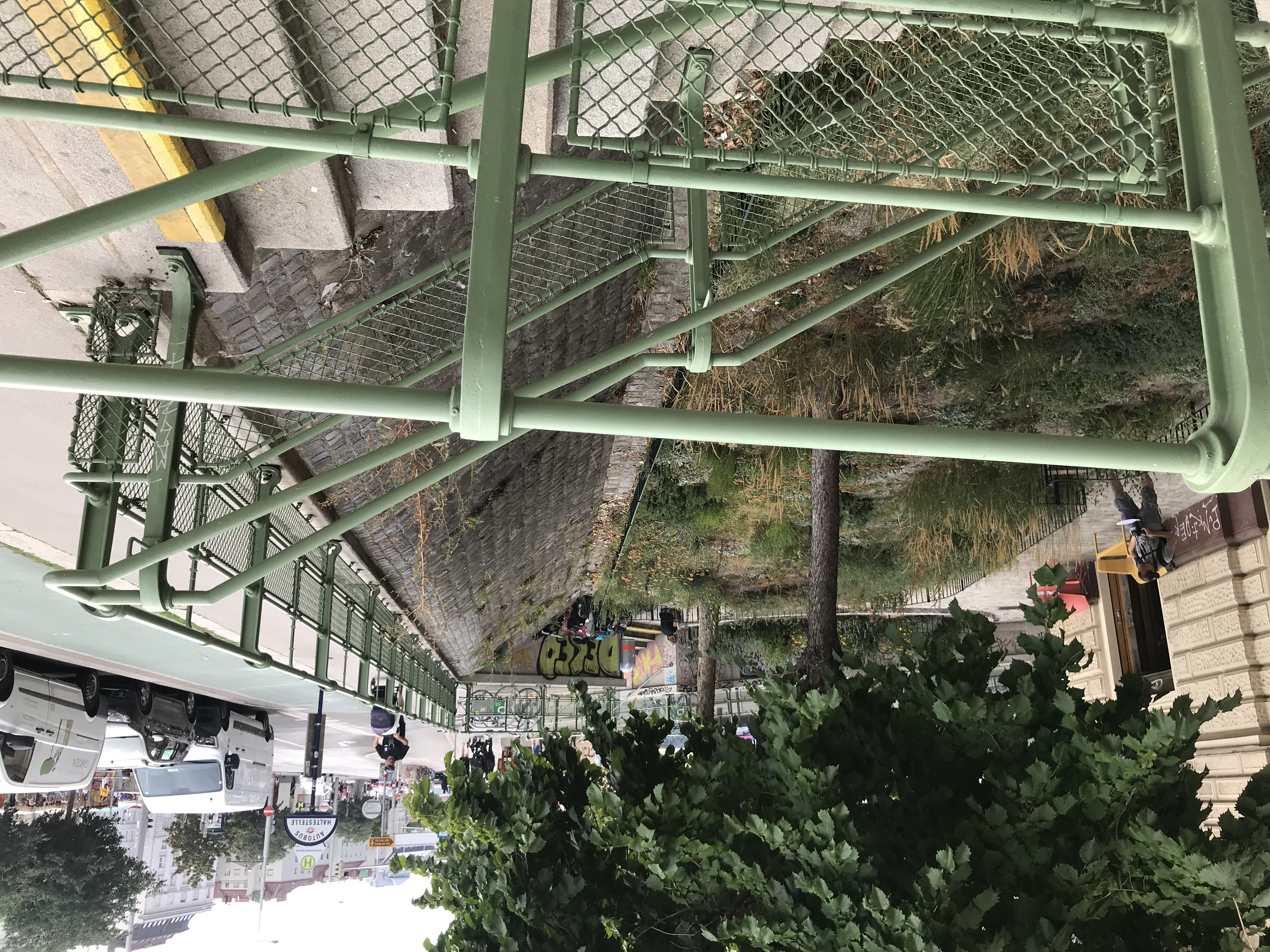 Farbfoto: Stiegen und Geländer im Vordergrund, dahinter eine schräge Böschung aus Steinquadern. Rechts oben eine Busstation und Geh-/Radwege.