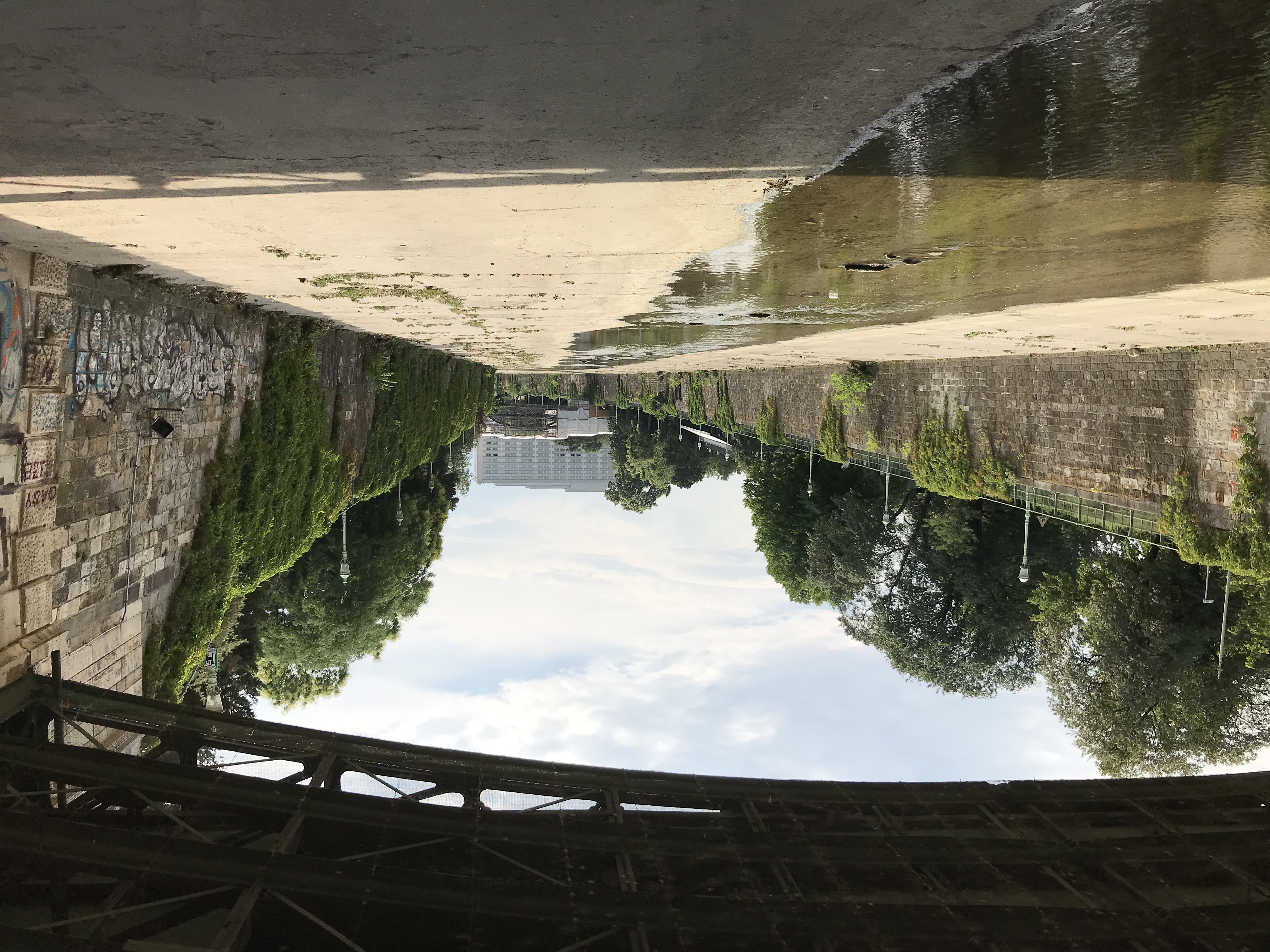 Blick aus einem Tunnelportal auf auf ein schmales Gewässer, links und rechts eingerahmt von sehr viel breiteren Betonflächen.