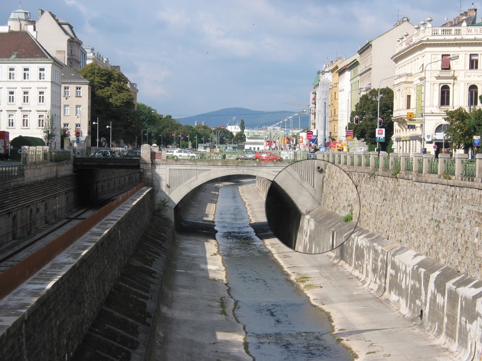 Steinbrücke über tiefen nach oben aber offenen, gemauerten Kanal. Links und rechts Häuser. Die Sole des Kanals ist mit ein wenig Wasser bedeckt.