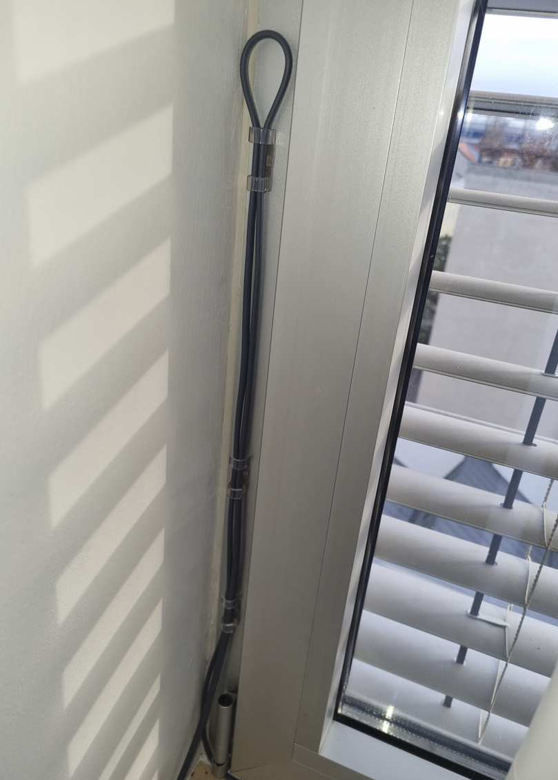 Silberner Fensterrahmen, schwarze dünne Schlauchschleife mit Klammern darauf befestigt
